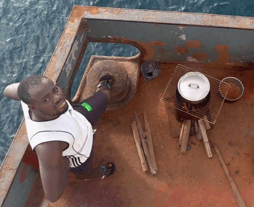 La tripulación se vio obligada a soportar meses sin un motor en funcionamiento y suministros básicos de alimentos. En la foto: un marinero cocina su cena quemando madera sobre el barco oxidado, 2022.